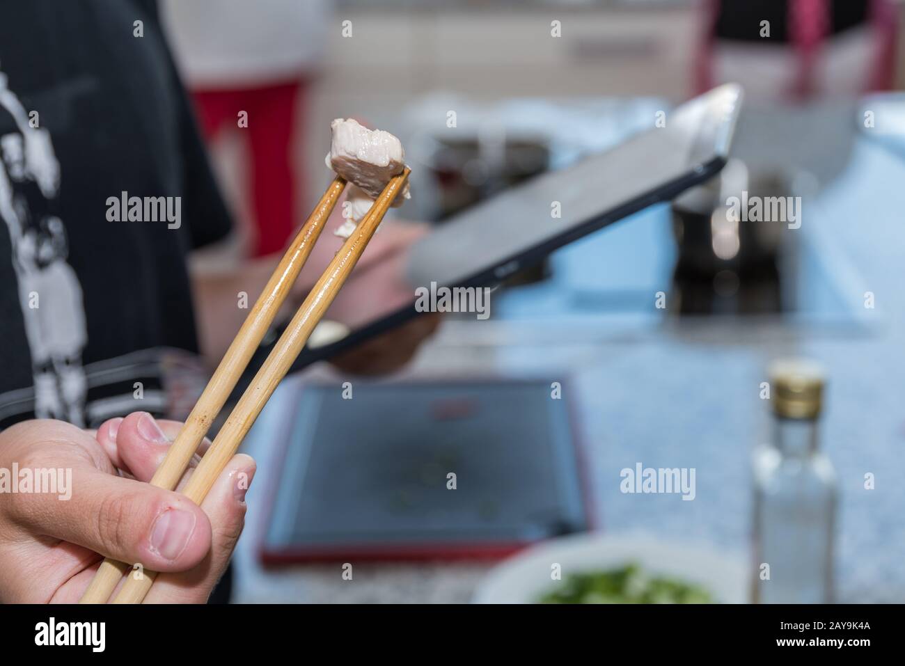 Kochanweisungen durch digitales Kochbuch - Essstäbchen mit Fleisch und Tablette Stockfoto