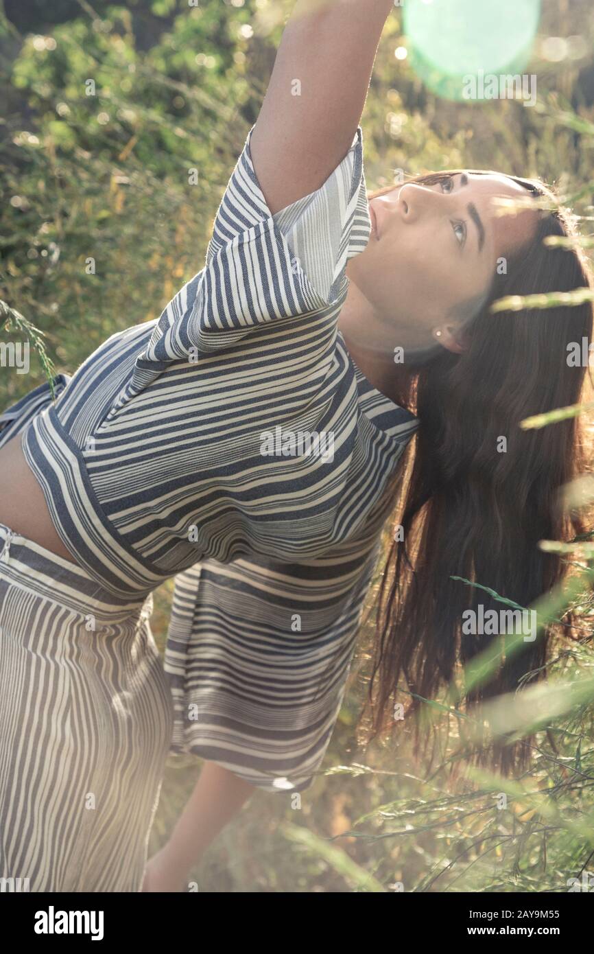 Hübsche Latina Frau in Sonnenschein und Blumenfeldern Stockfoto