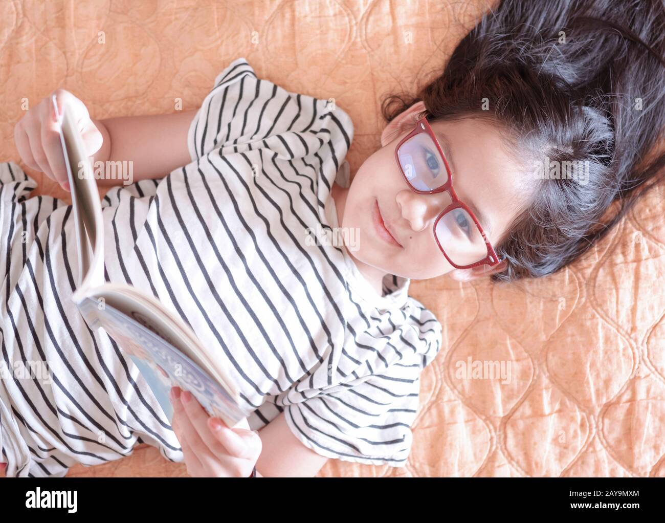 Ein Mädchen, das sich an einem Wochenende hinlegt und ein Buch liest Stockfoto