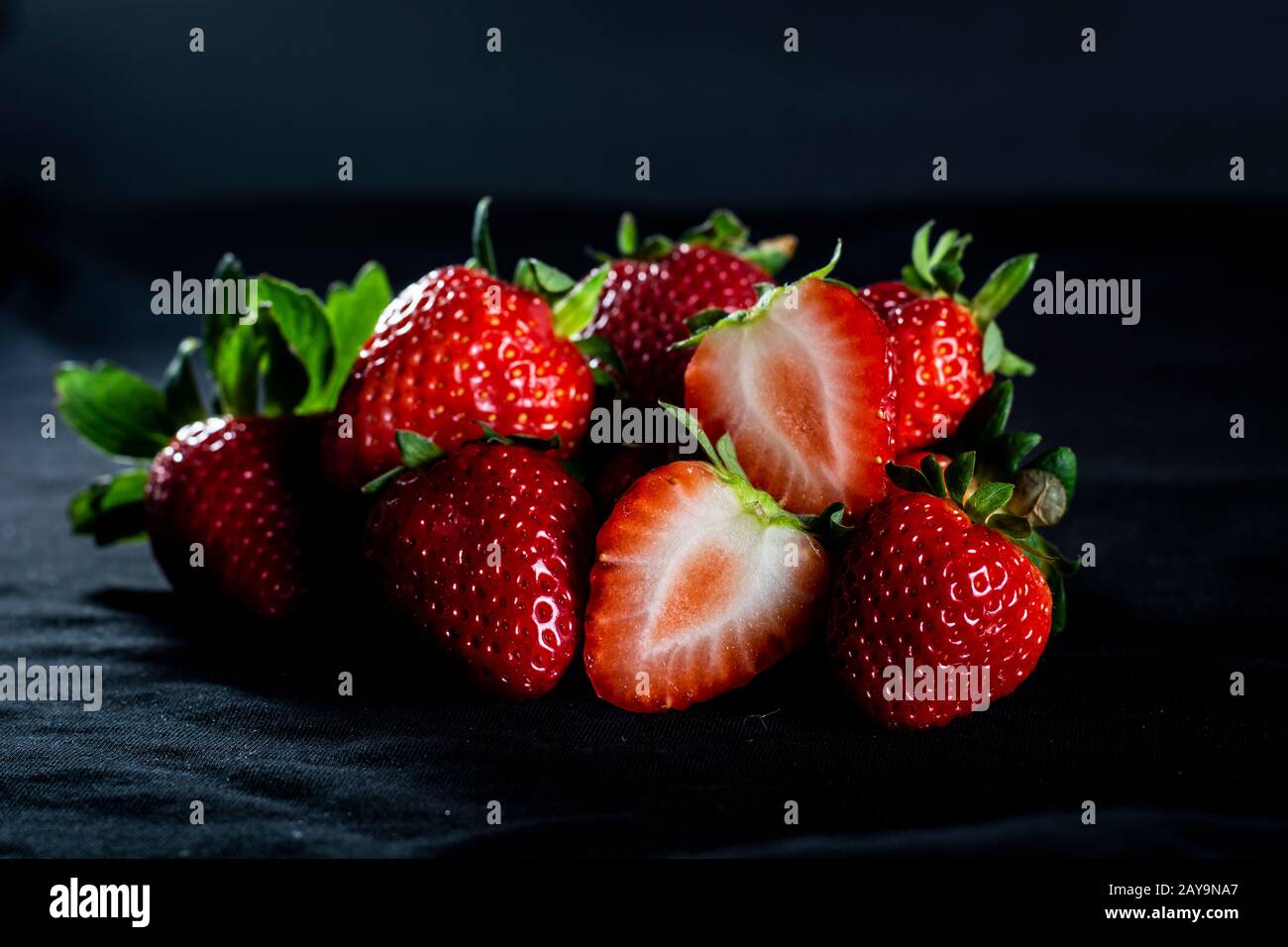 Erdbeeren mit schwarzem Hintergrund und leichtem Regen Stockfoto