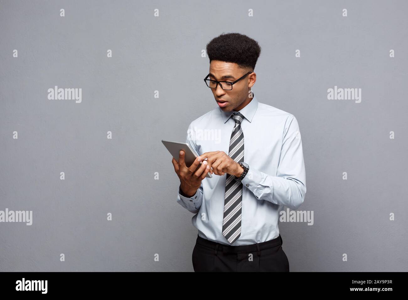 Geschäftskonzept - Glücklich aussehenden professionelle afrikanische amerikanische Geschäftsmann schockierend mit etwas auf Tablet. Stockfoto