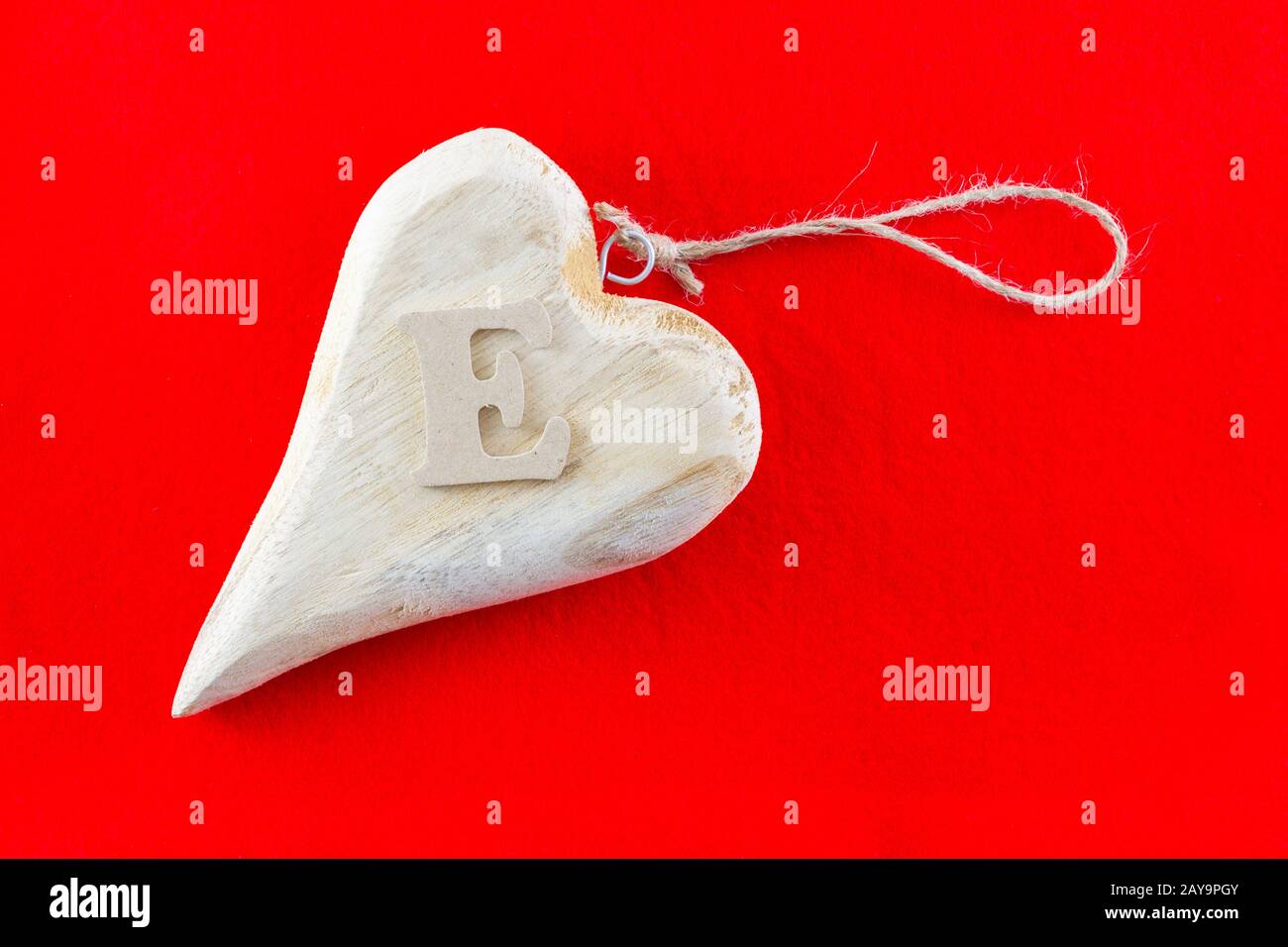 Holzherz mit Buchstabe E auf rotem Hintergrund für Valentinstag Stockfoto