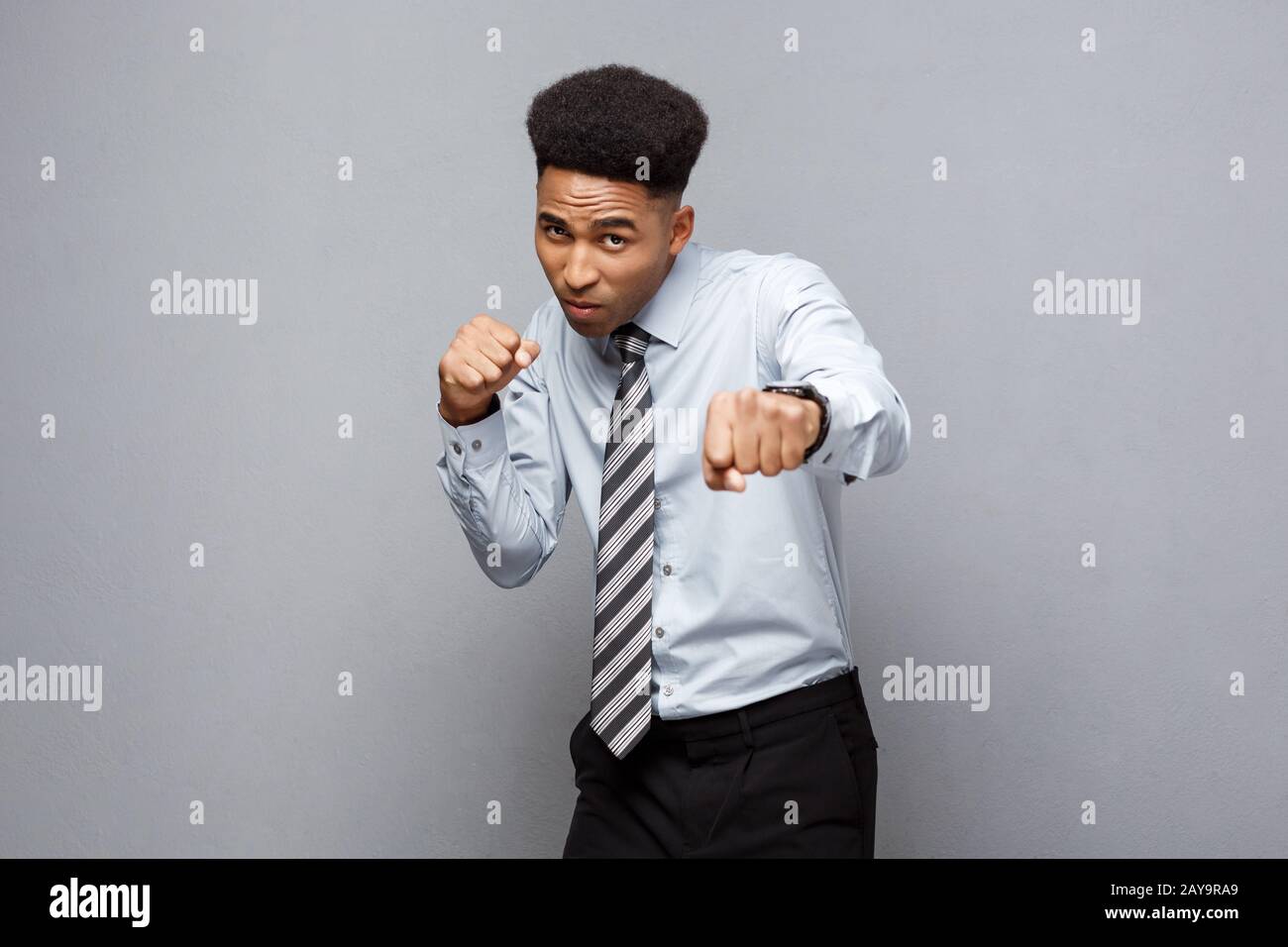 Geschäftskonzept - Zuversichtlich, fröhlicher junger afrikanischer Amerikaner im Boxen poseture über grauen Hintergrund. Stockfoto