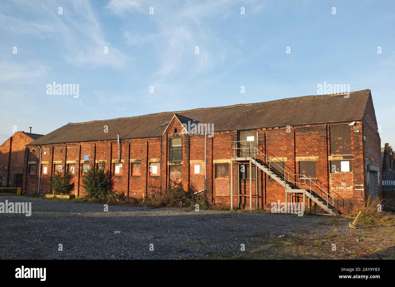 Ein altes vergangener Ziegelbau mit aufgesetzten Fenstern und Stahltreppe Stockfoto