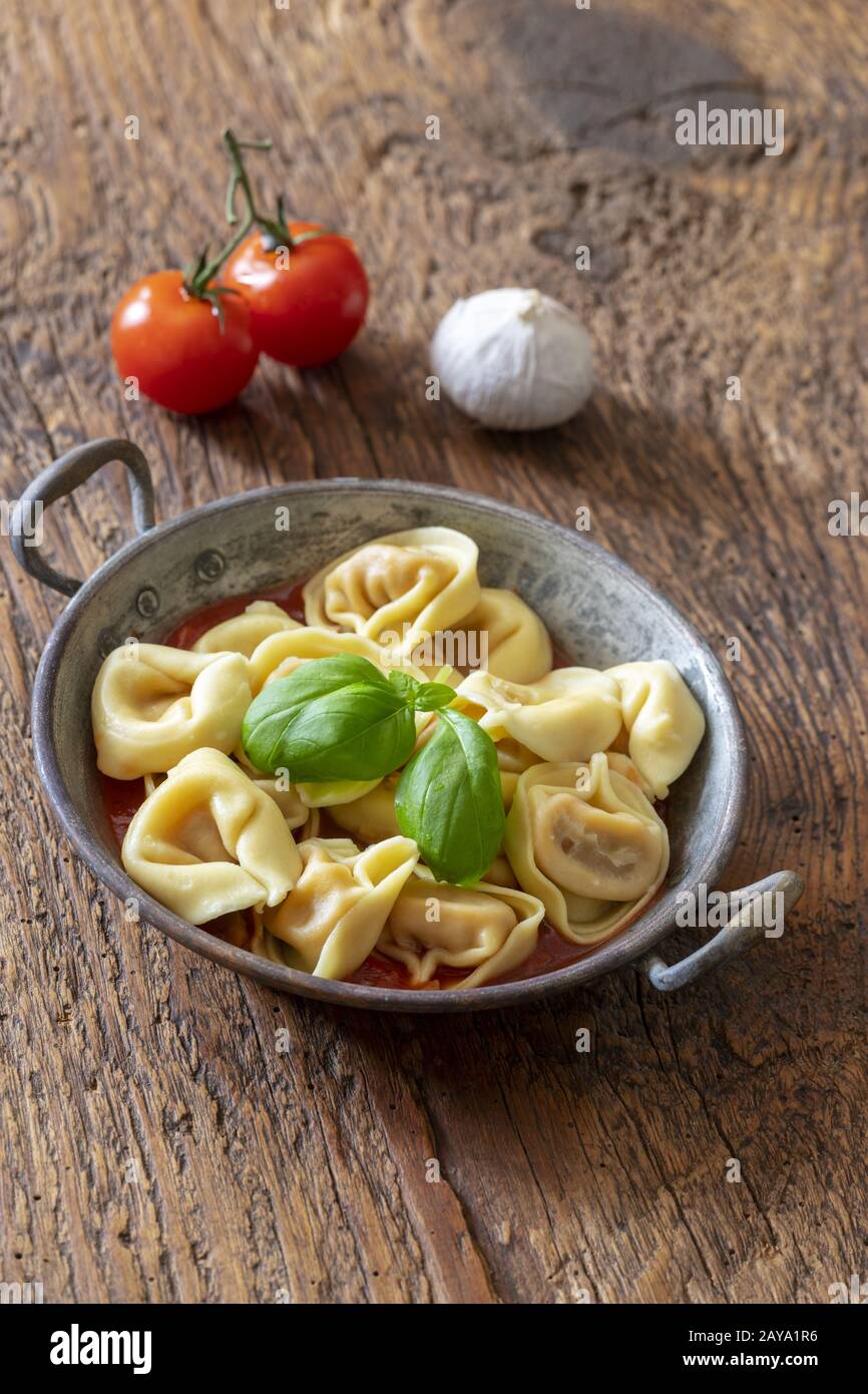 Tortellini auf Holz mit Tomatensauce Stockfoto