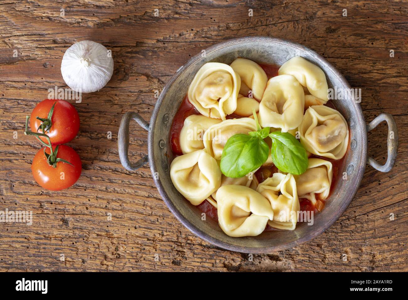 Tortellini auf Holz mit Tomatensauce Stockfoto