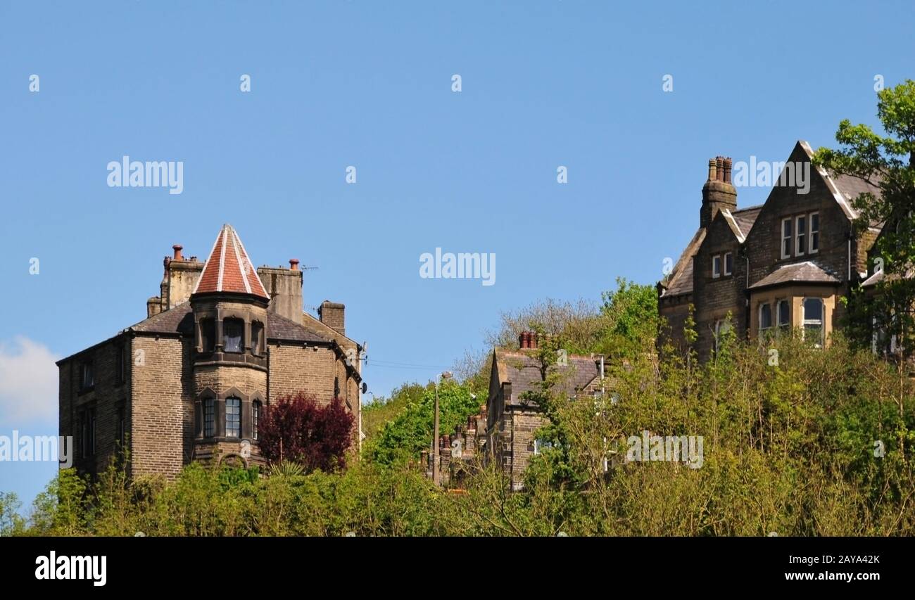 Hohe Häuser aus Stein im Gotischen Stil in der Waldlandschaft i hebden Brücke West yorkshire mit blauem Himmel Stockfoto