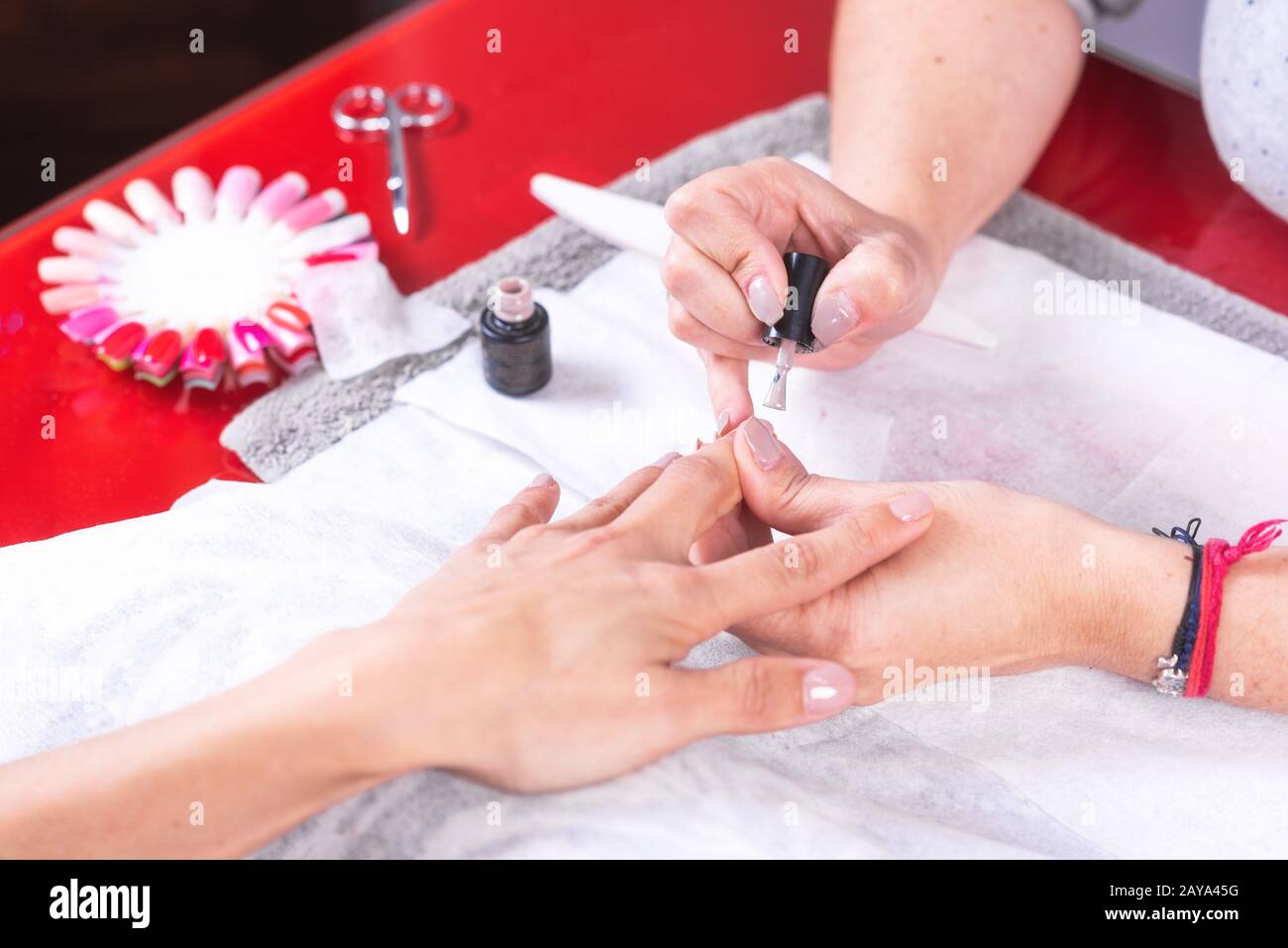 Professioneller Manikurist, der mit Arbeitswerkzeugen arbeitet und in einem Frauennägelsalon nagellack aufgibt. Stockfoto