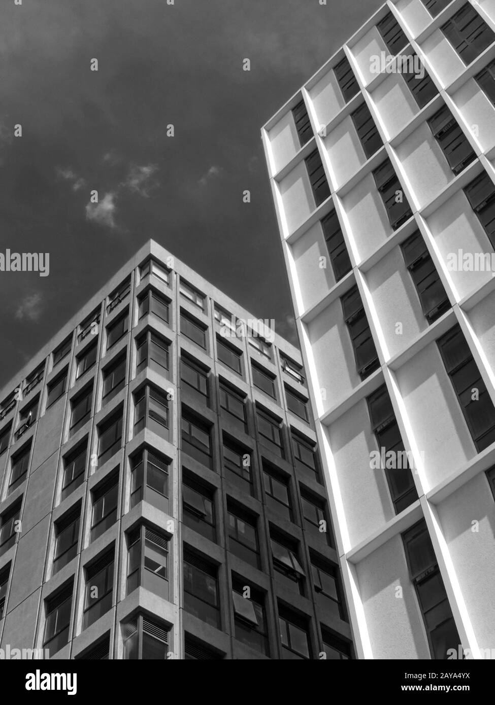 Monochromer vertikaler Blick auf weiße, weiße Betonbauten bewölkter Himmel Stockfoto