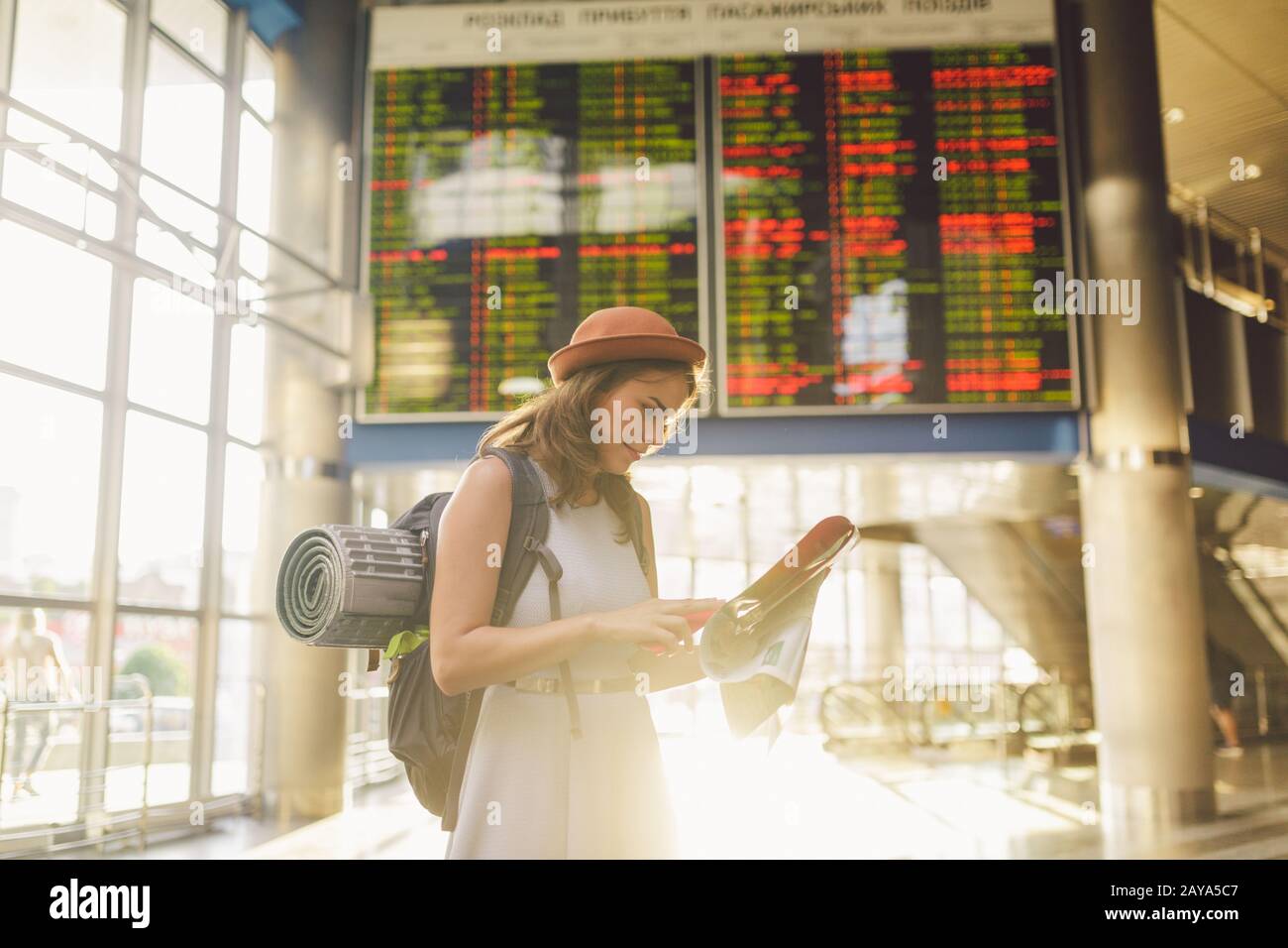 Themenreise und Transport. Schöne junge kaukasische Frau im Kleid und Rucksack im Inneren des Bahnhofs Terminal lo Stockfoto