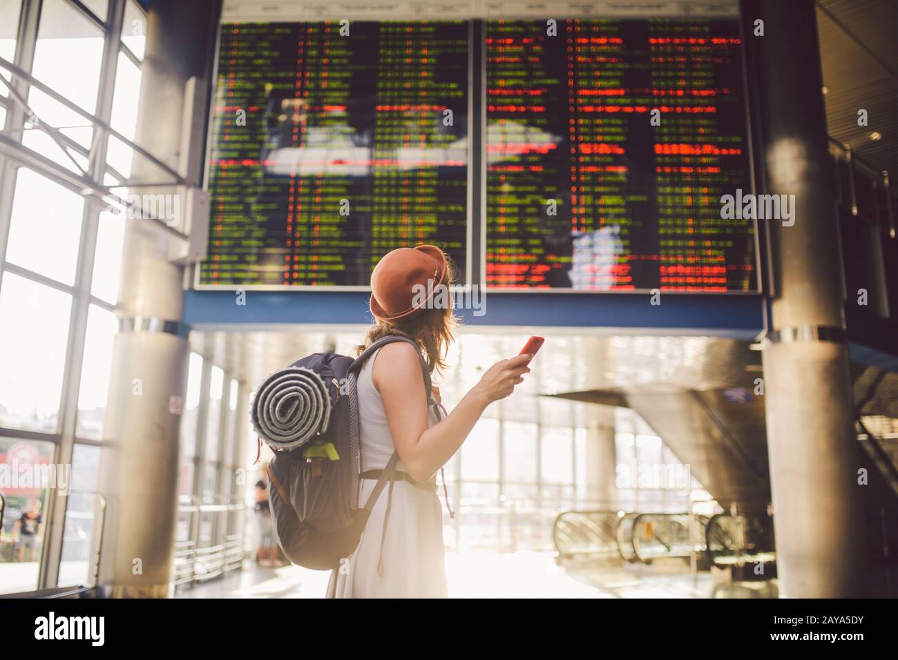 Themenreise und Tranosport. Schöne junge kaukasische Frau im Kleid und Rucksack, die im Bahnhof oder Terminal Loo steht Stockfoto