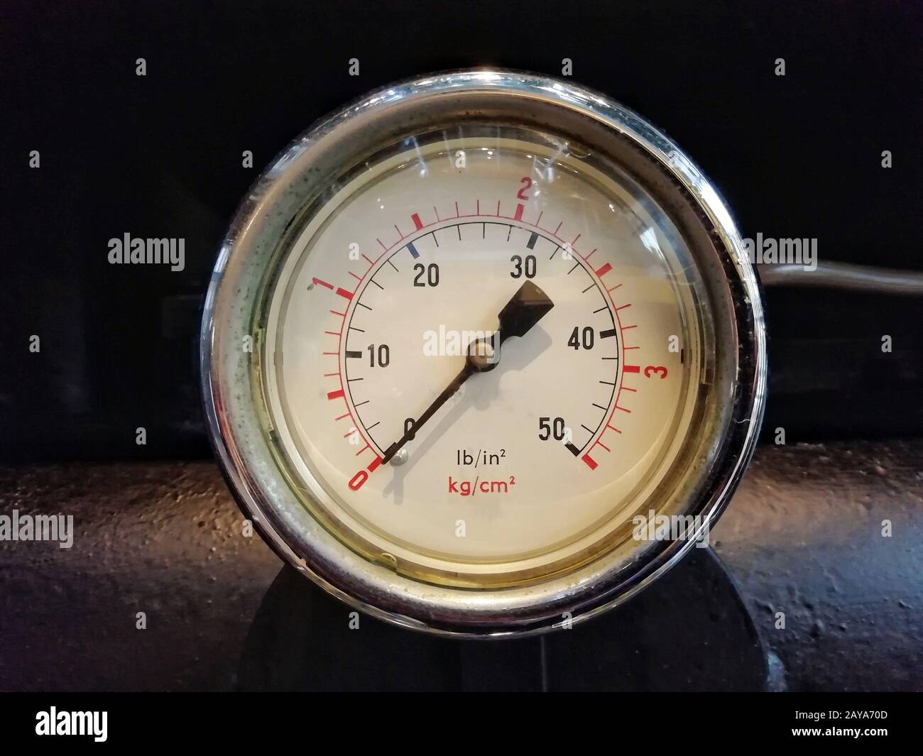 Ein rundes, glänzendes Manometer mit Zahlen, die in psi und metrisch auf dem Messrad auf Industriemaschinen markiert sind Stockfoto