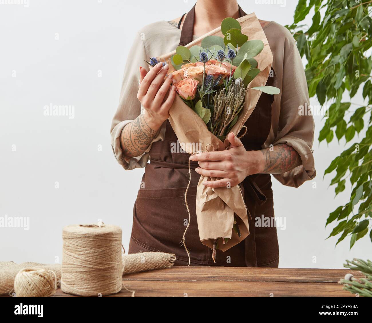 Frau Floristin mit frischem, schönen, handgefertigten Blumenstrauß aus fesh duftenden Blumen ang grüne Blätter auf hellem Wandhintergrund, Kopie Stockfoto