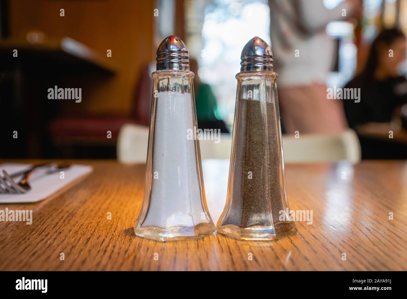 Salz und Pfeffer - Pfefferstreuer und Salzschüttler, die beliebtesten Gewürze, schwarzer Pfeffer und Salz auf dem Tisch im Restaurant Stockfoto