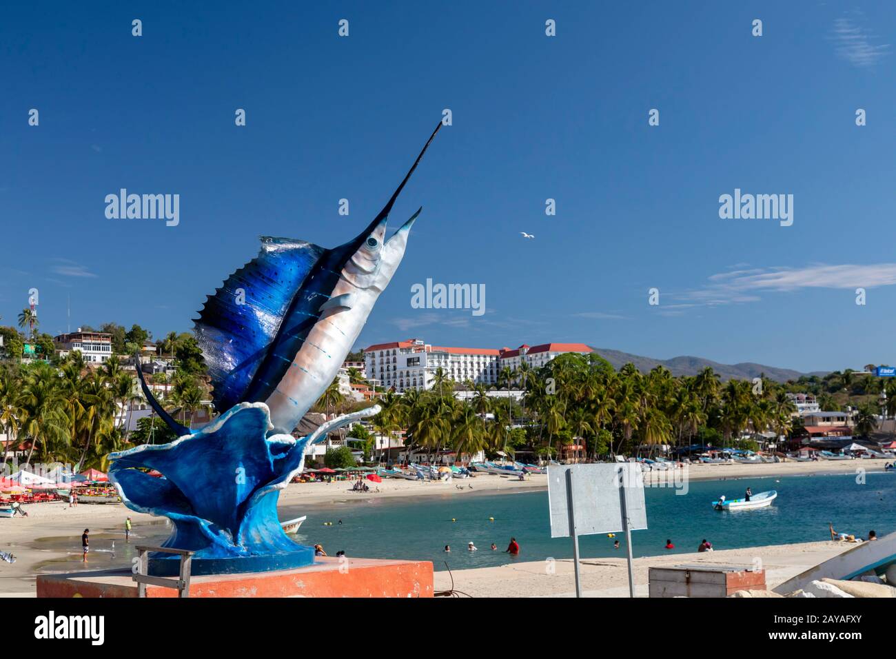 Puerto Escondido, Oaxaca, Mexiko - EINE Statue eines Segelfisches über dem Playa Principal oder dem Hauptstrand am Pazifischen Ozean. Stockfoto