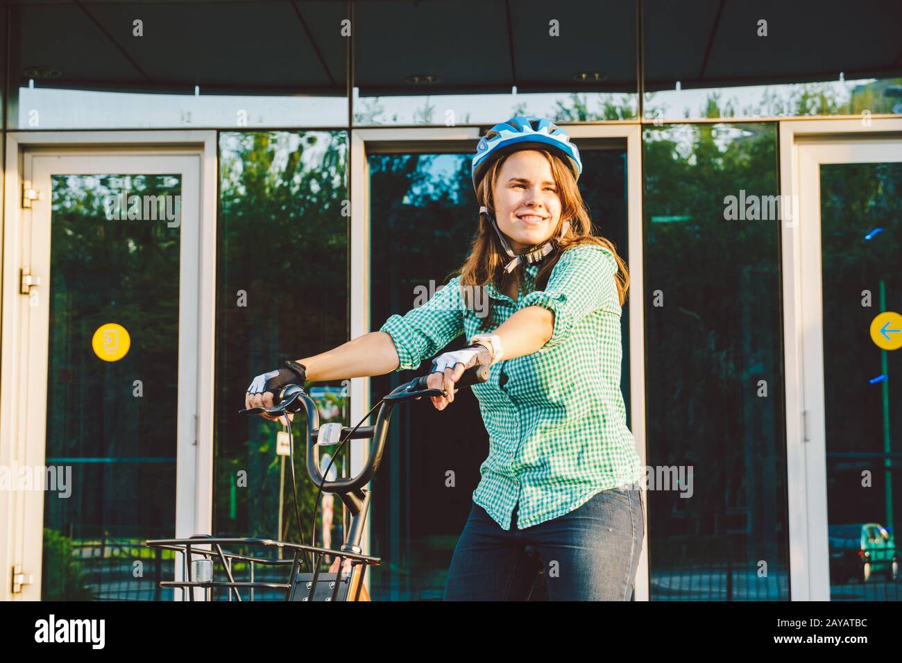Thema für die Arbeit am Fahrrad. Eine junge kaukasische Frau kam mit einem umweltfreundlichen Transportfahrrad ins Büro. Mädchen in a B. Stockfoto