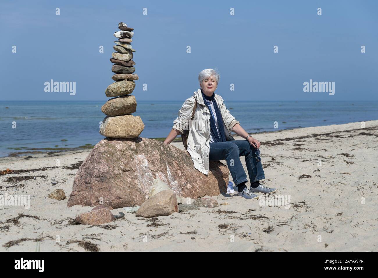 Senior neben einer Steinpyramide sitzend Stockfoto