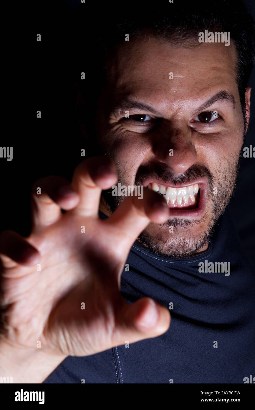 Aggressiver Mann greift mit der Hand in einer gruseligen Nachtszene an. Stockfoto