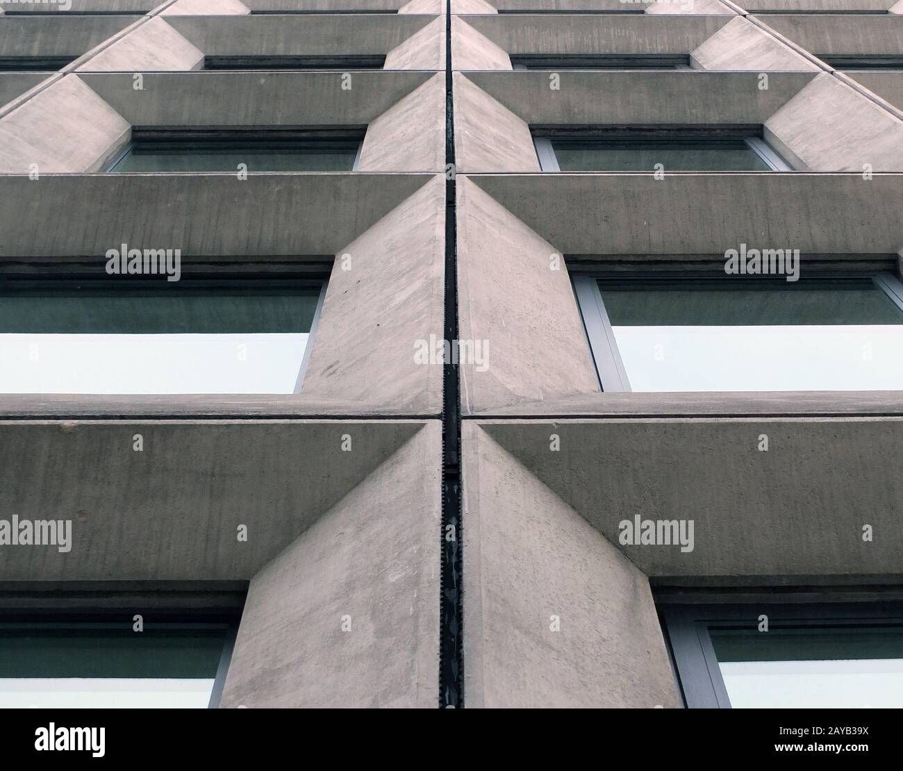 Perspektivischer Blick auf geometrische Winkelbetonfenster an der Fassade eines Gebäudes im brutalistischen Stil der 1960er Jahre Stockfoto