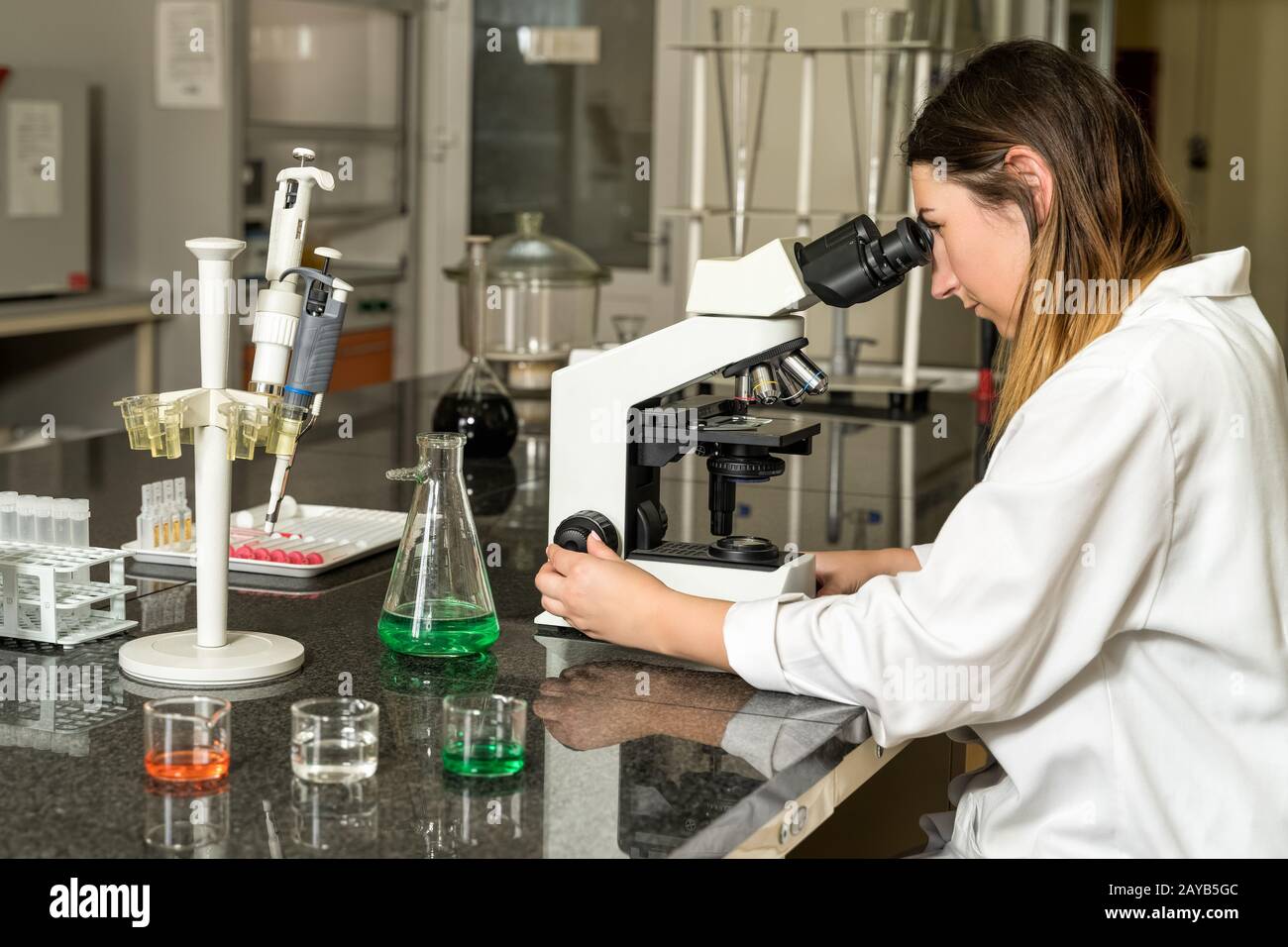 Labortechniker im mittleren Alter, die an einem Mischmikroskop arbeiten Stockfoto