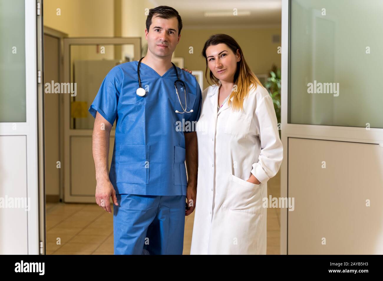 Portrait von Frauen und Männern in weißer Robe und blauen Schruben auf verschwommenem Krankenhaus-Korridor zurück Stockfoto