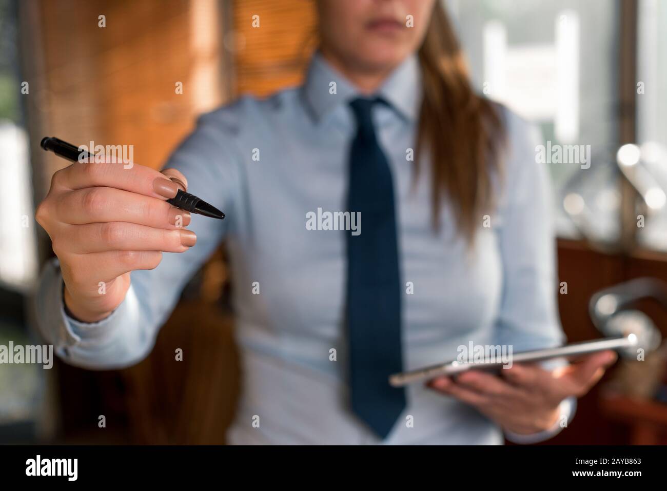 Verschwommene Frau im Hintergrund, die den Stift in der Hand hält. Kopieren Sie den Bereich mit dem Finger, der darin zeigt. Geschäftsfrau mit Hemd und ti Stockfoto