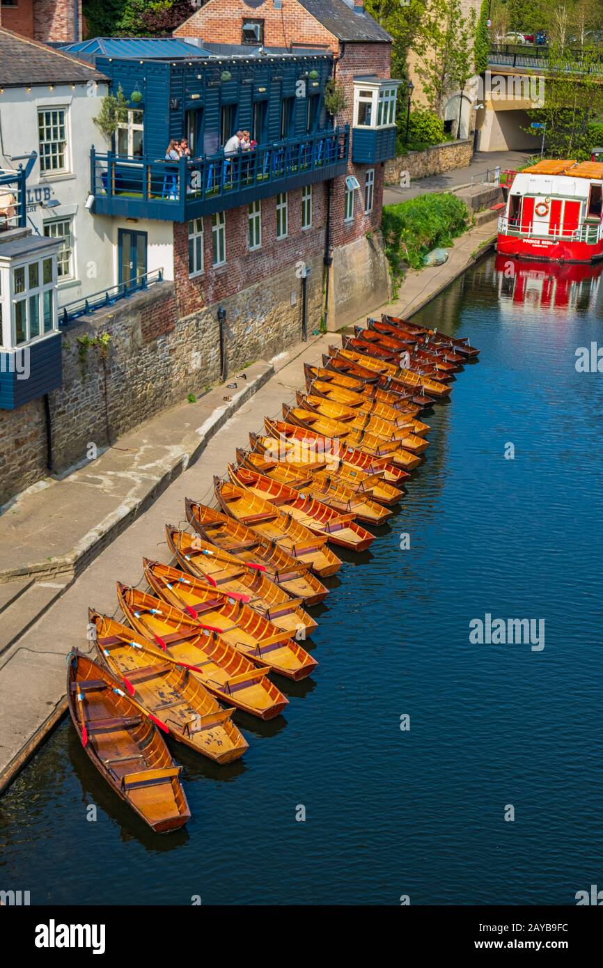 Eine Reihe von vermoorten Ruderbooten am Ufer des Flusses tragen in der Nähe eines Bootsklubs in Durham, Großbritannien an einem schönen Frühlings-Nachmittag Stockfoto
