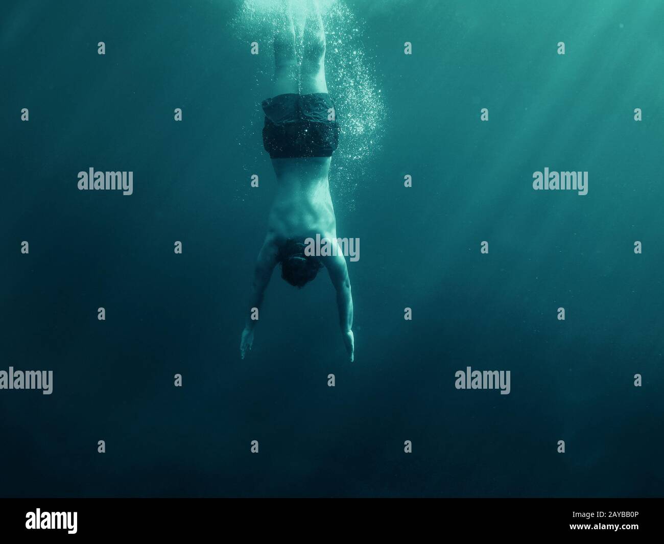 Mann springt ins Wasser. Unterwasseraufnahmen. Urlaub, Sport und aktives Lifestyle-Konzept. Stockfoto