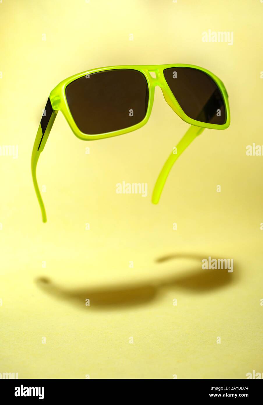 Grün schwimmend in der Luftsonnenbrille auf gelbem Hintergrund. Stockfoto