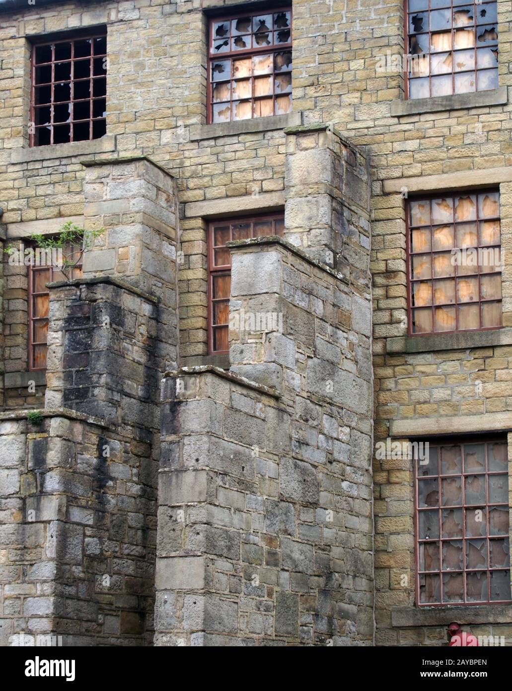 Ein großes verfallenes altes Fabrikgebäude mit aufgesetzten und durchbrochenen Fenstern Stockfoto