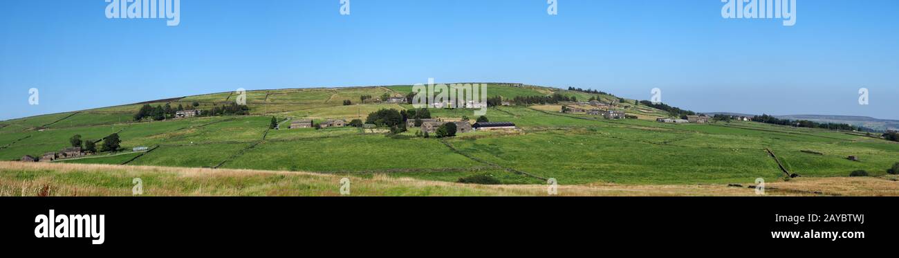 Lange Panoramasicht auf grüne Felder und Dorfsteinhäuser im rollenden Westen yorkshire Dales Landschaft in Colden mit blauer Summe Stockfoto