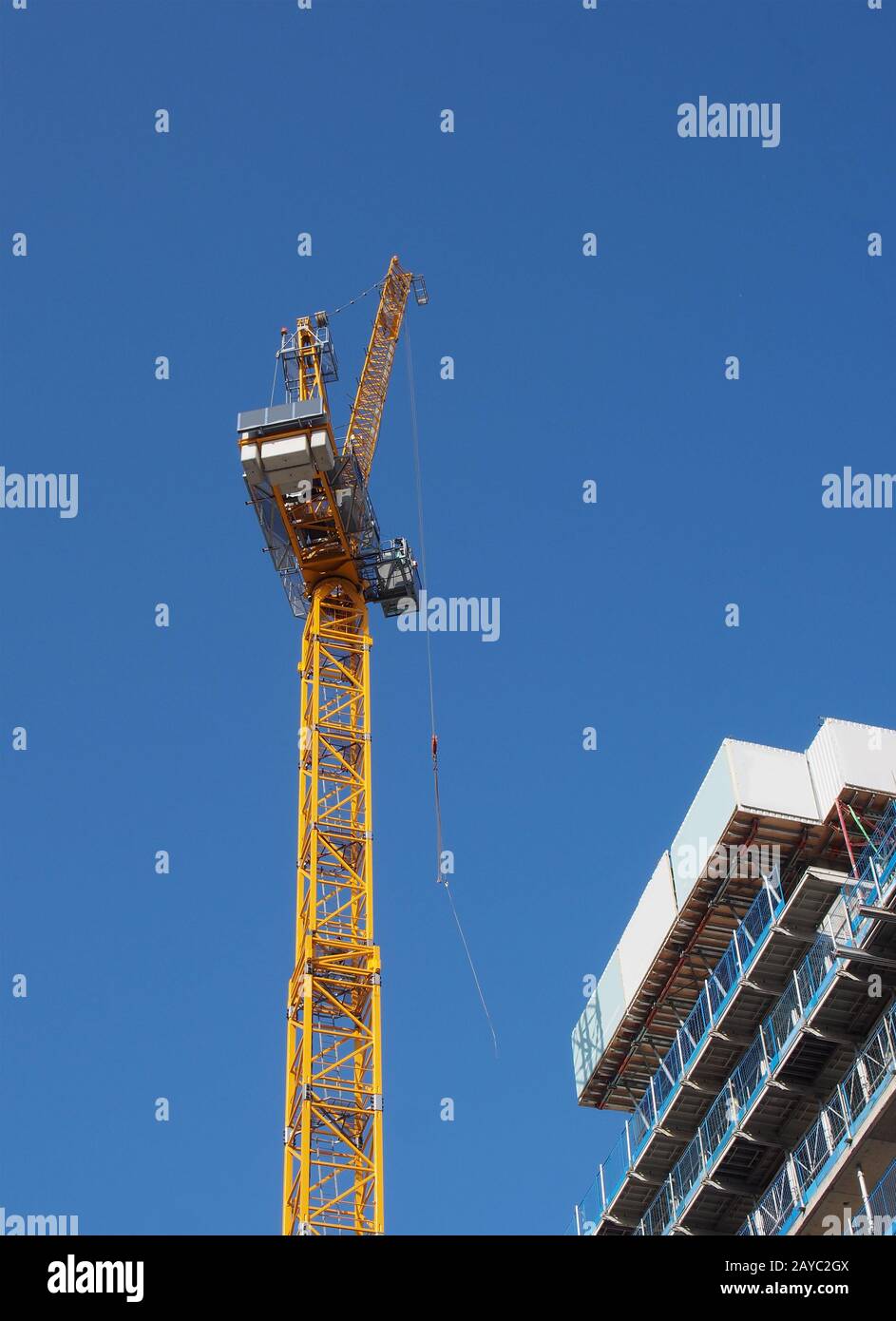 Blick auf einen hohen Turmkran, der auf großen Baustellen gegen einen blauen Himmel arbeitet Stockfoto