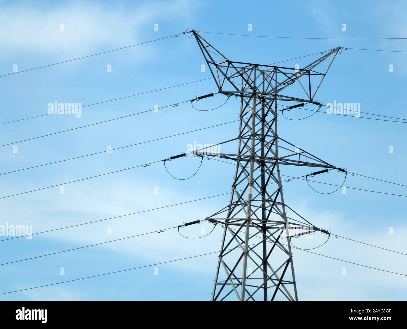 Hoher Elektrizitätspylon aus Metall mit mehreren Kabeln gegen einen blauen bewölkten Himmel Stockfoto