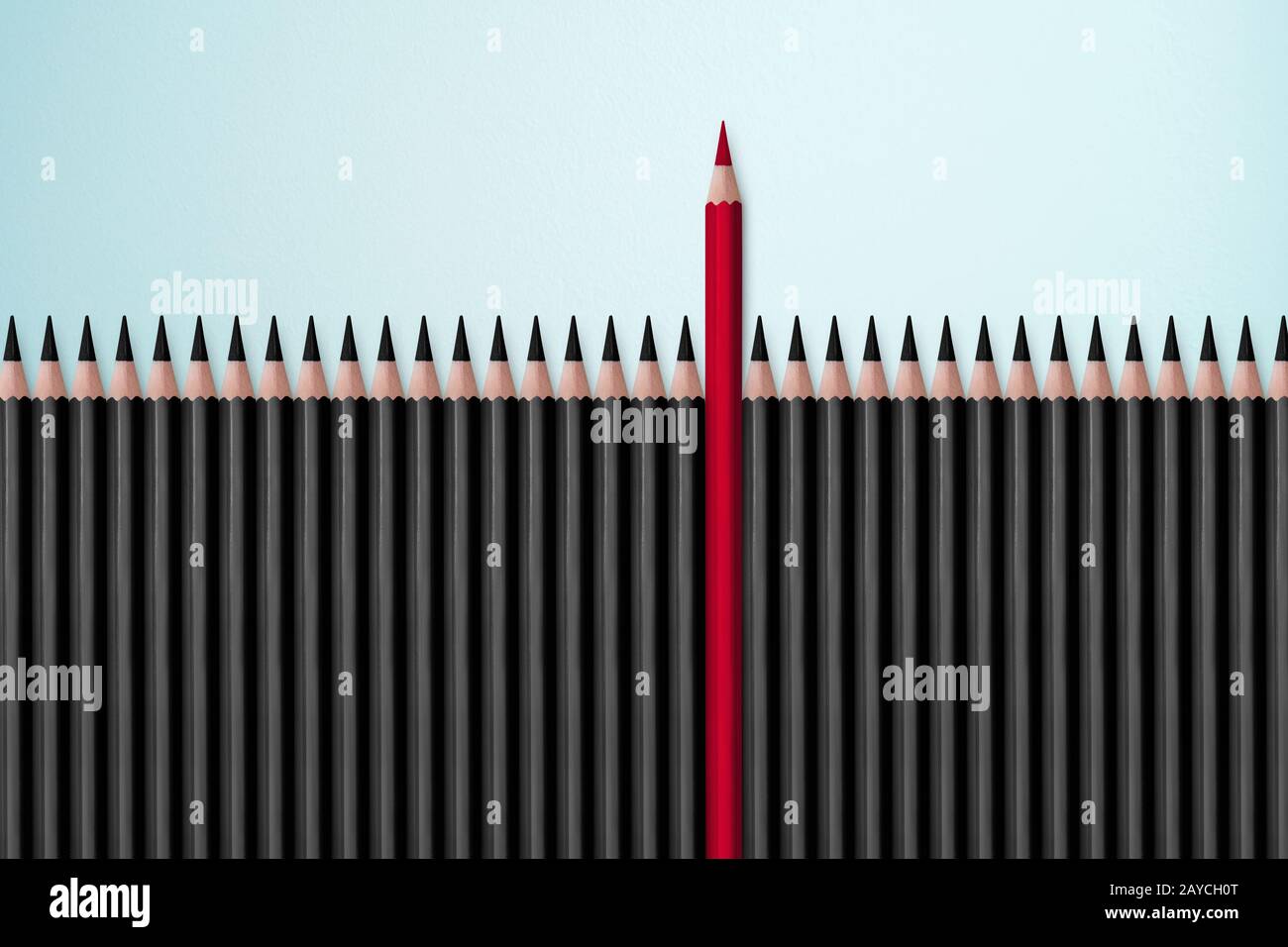 Roter Bleistift, der sich vor vielen identischen schwarzen Fellows auf weißem Tisch abhebt. Führung Stockfoto