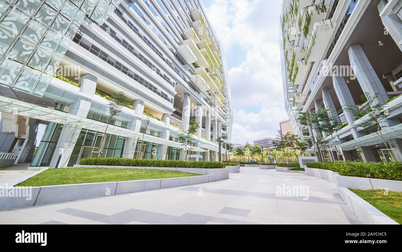 Niedriger Blickwinkel Blick auf das leere Straßenbelag und modernes Bürogebäude mit grünem Öko-Konzept Balkon. Stockfoto