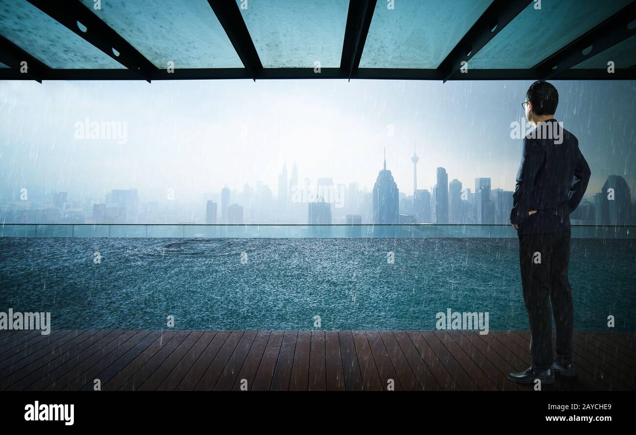 Geschäftsleute, die vor einem Swimmingpool auf dem Dach mit wunderschönem Blick auf die Skyline der Stadt blicken und denken Stockfoto