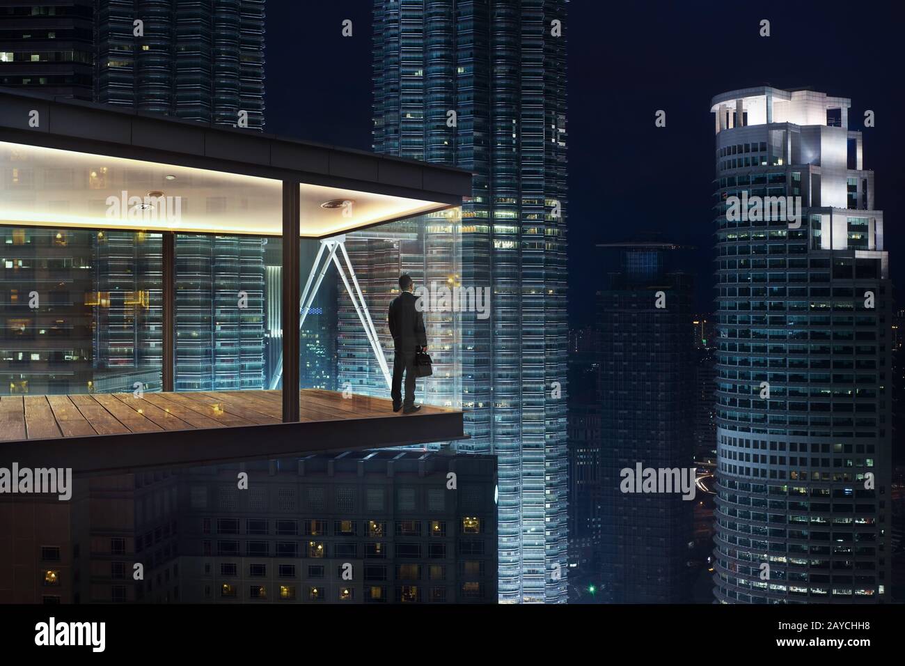 Geschäftsmann in einem modernen Himmel Büro bei Nacht mit Blick auf die schöne Stadt Skyline. Stockfoto