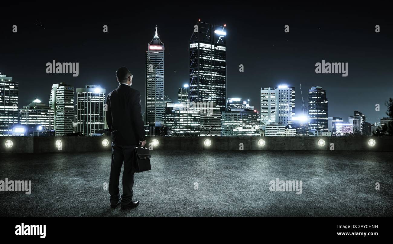 Geschäftsleute, die auf dem Dach mit modernem Hintergrund der Skyline der Stadt hinschauen und denken Stockfoto