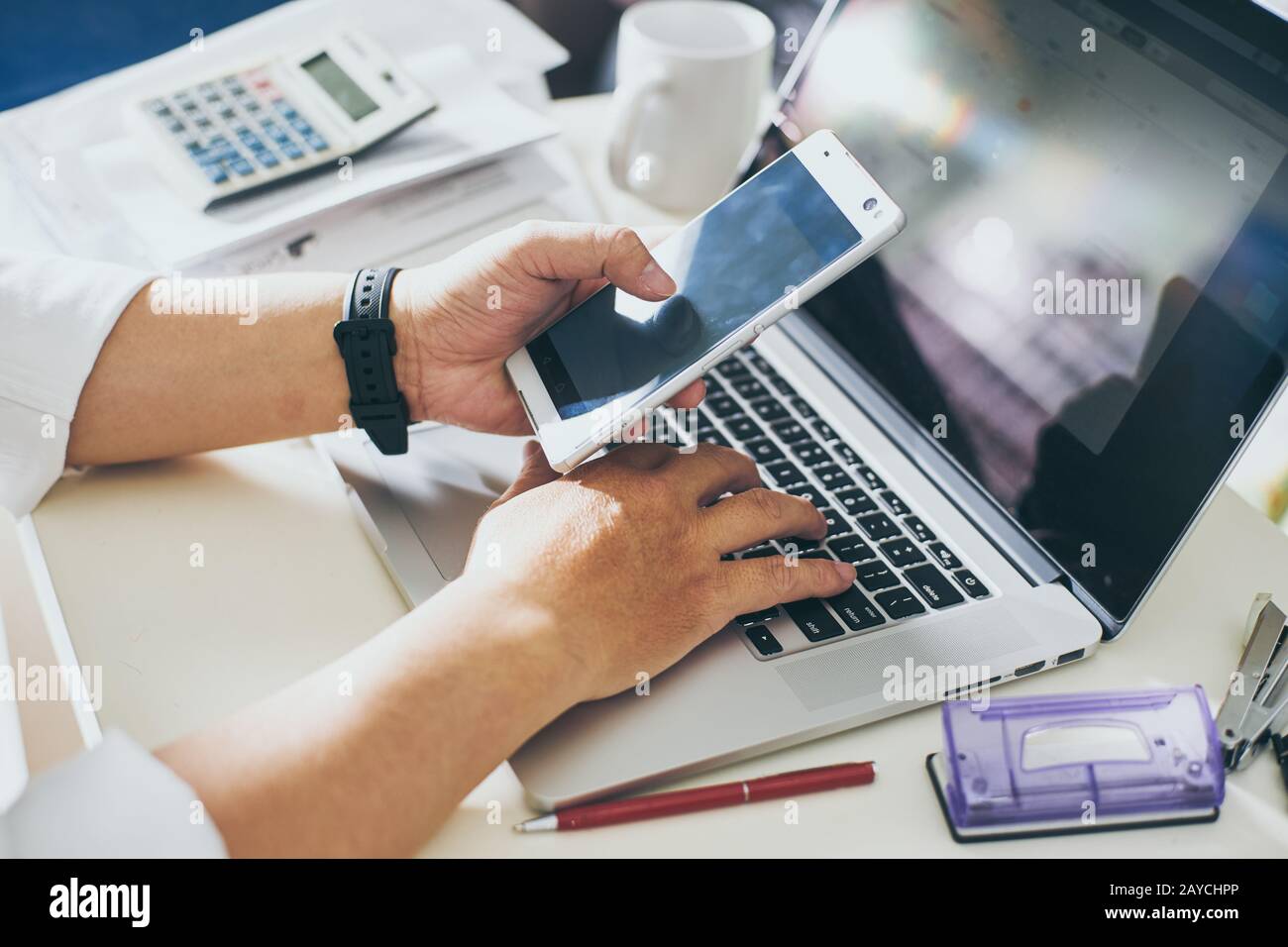 Geschäftsleute verwenden ein Smartphone und geben die Daten auf einen Laptop ein Stockfoto