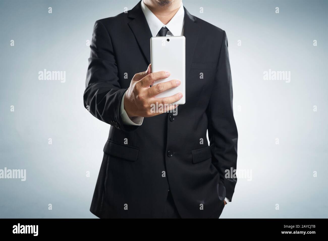 Intelligente Geschäftsmann im schwarzen Anzug stehen während machen eine Selfie per Handtelefon auf grauem Hintergrund. Stockfoto