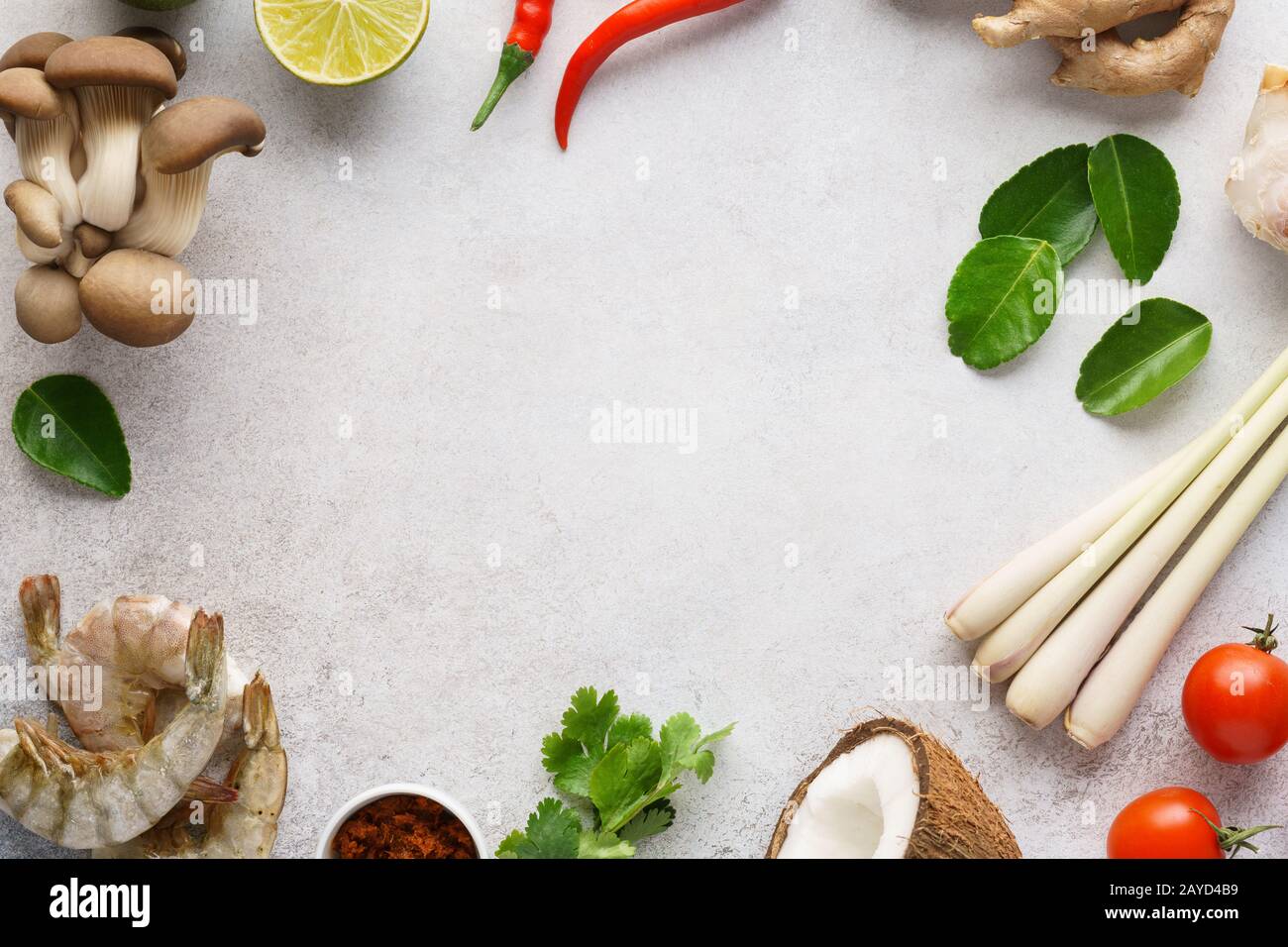 Rahmen aus verschiedenen Zutaten für die Zubereitung von Tom Yum - traditionelle würzige thailändische Suppe mit Pilzen, Garnelen oder Garnelen und Kokosmilch. Hintergrund mit Stockfoto