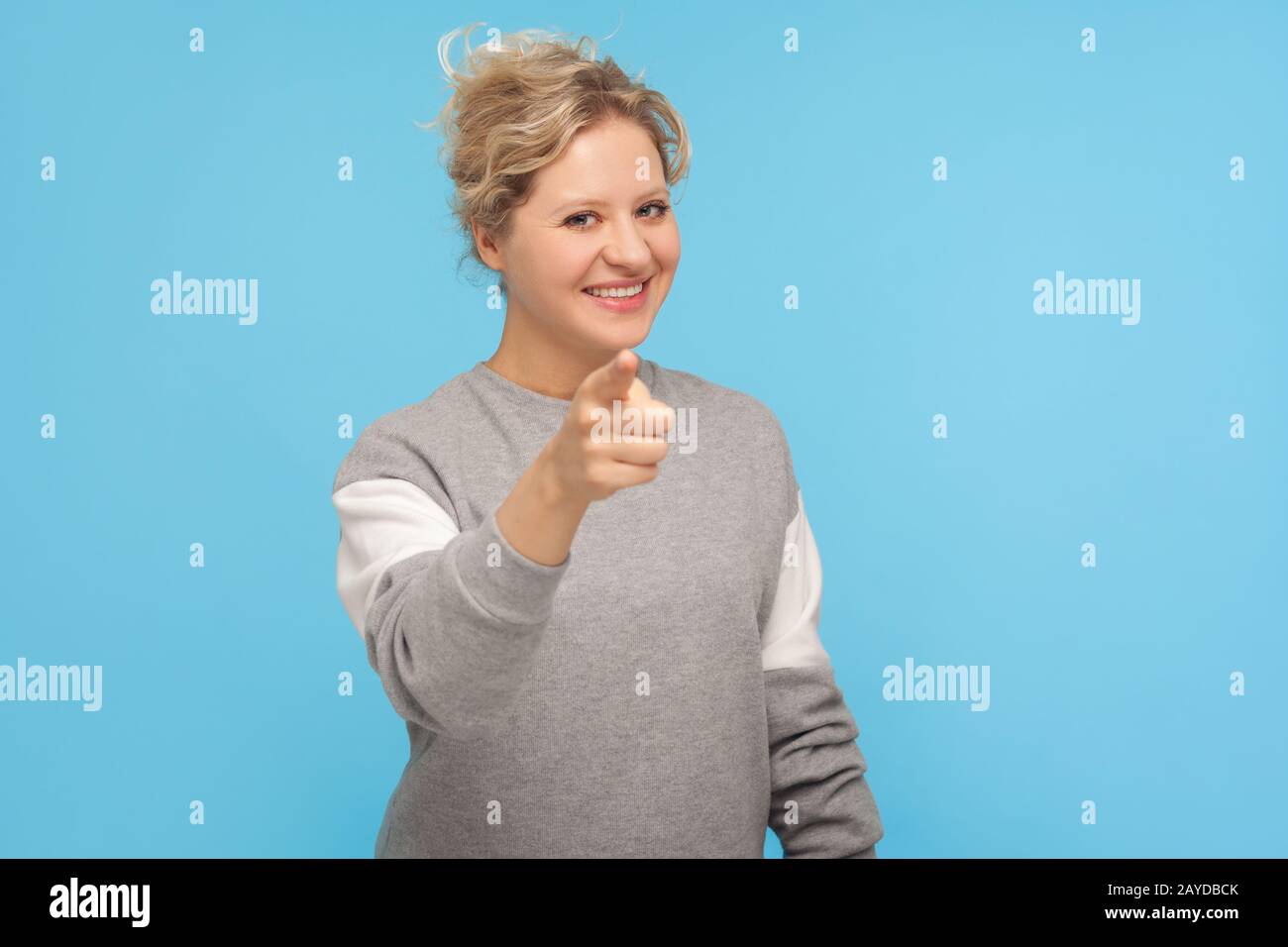 HE, du! Fröhliche Frau mit kurzen lockigen Haaren in Sweatshirt zeigen und Kamera mit glücklichem Gesicht sehen, ich brauche Sie Konzept, gute Wahl zu treffen. In Stockfoto