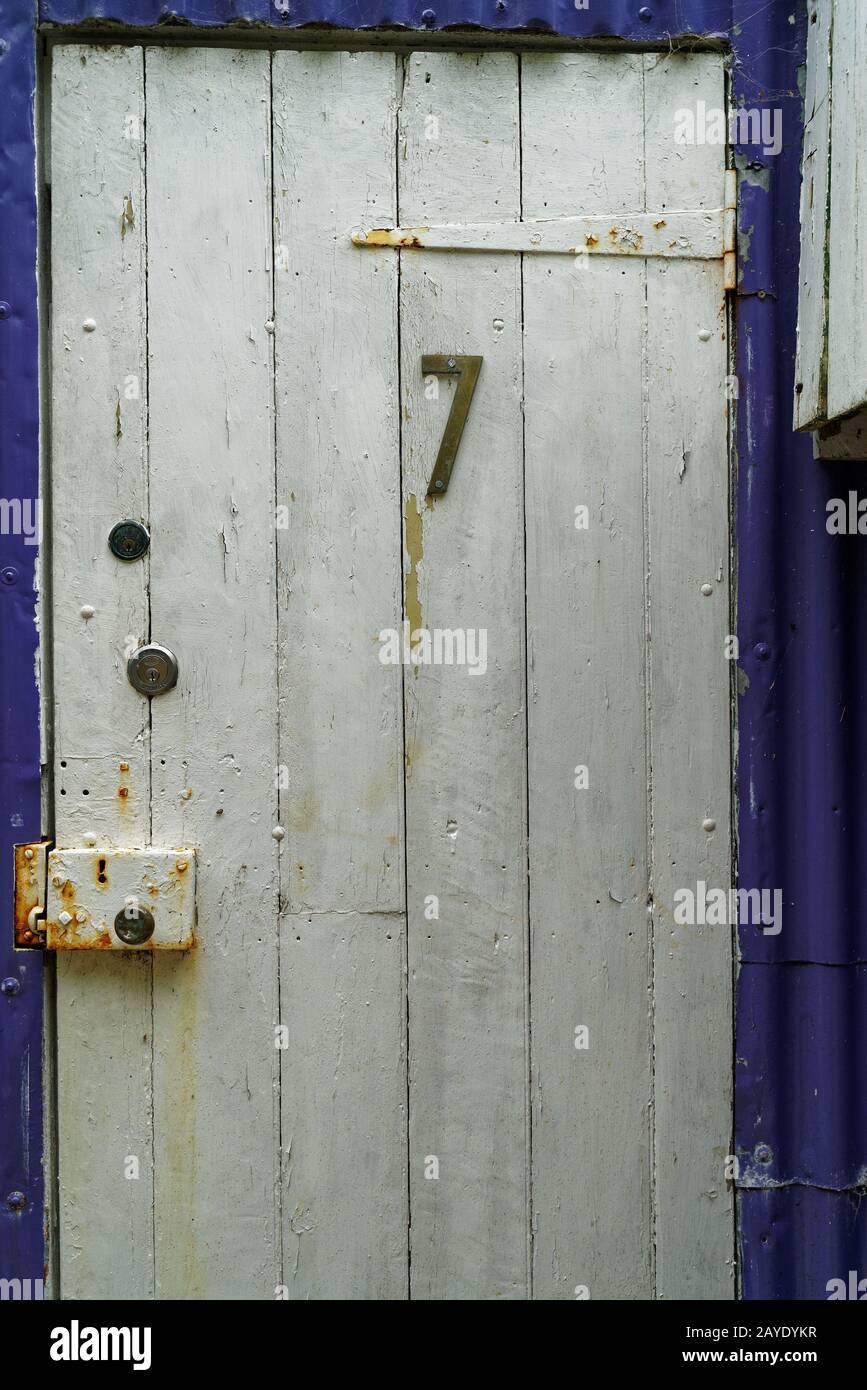 Die Nummer 7 auf einer rustikalen weißen Schuppentür. Stockfoto