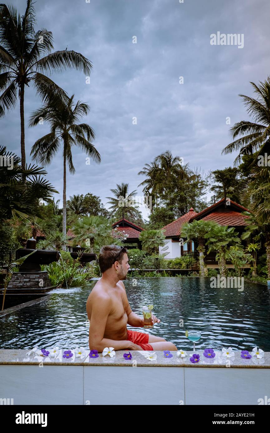 Kerl trinkt während des Urlaubs in Thailand Cocktails am Pool Stockfoto