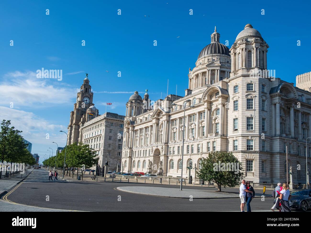 Liverpool Waterfront mit Touristen, die sich und die drei Graces Gebäude in Sicht an einem schönen Sommernachmittag genießen Stockfoto