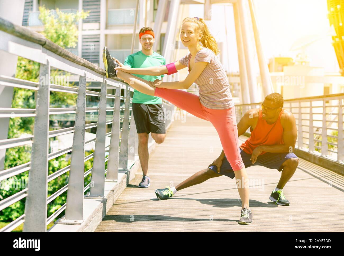 Eine Gruppe von Freunden, die sich ausstrecken, bevor sie in einer Brücke im Freien joggen - Multi Ethnic Fit People Training im städtischen Wettbewerb - neuer gesunder Lifestyle-Trend Stockfoto