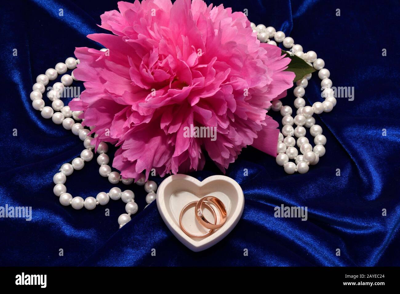 Zwei Trauringe für Braut und Bräutigam und Pfingstrose. Stockfoto