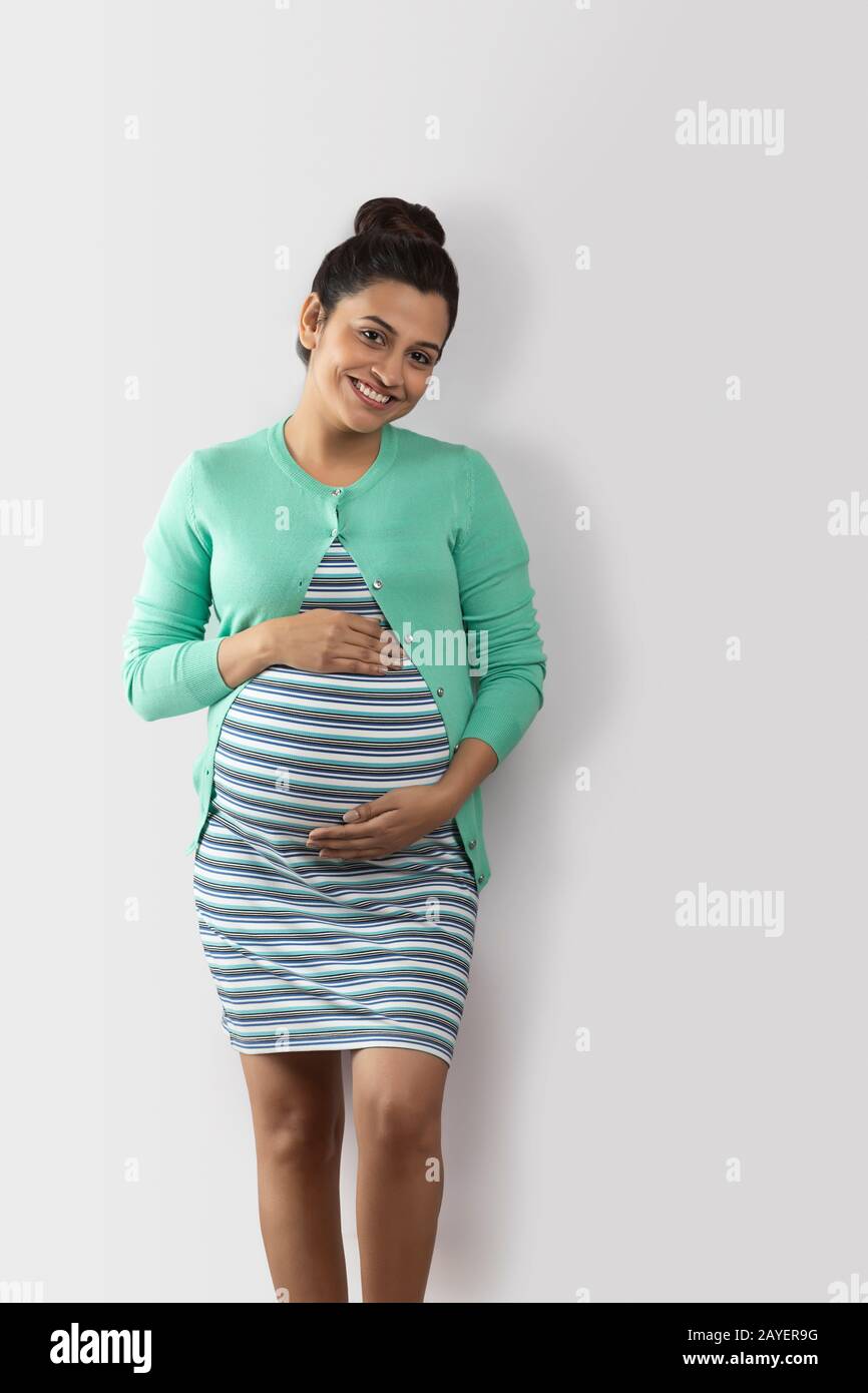 Fröhliche schwangere Frau mit ihren Händen auf dem Bauch. Stockfoto