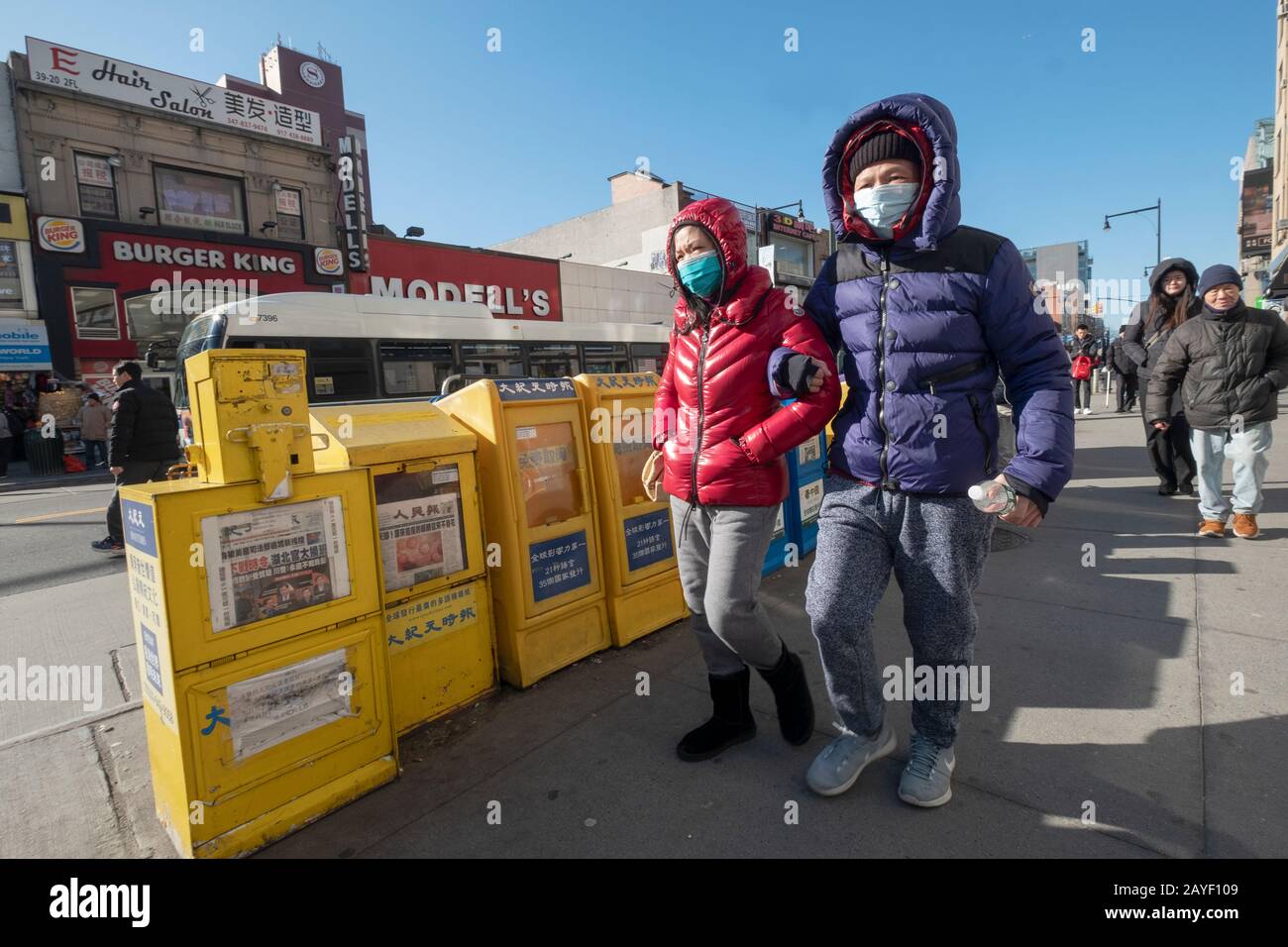 Ein vermutlich verheiratetes chinesisches amerikanisches Paar spaziert mit chirurgischen Masken zusammen. In Chinatown, Flushing, Queens, New York City. Stockfoto