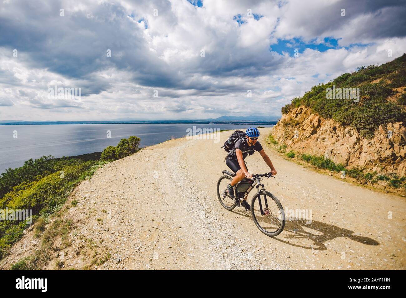 Junger Kerl, der in Spanien auf einem Fahrradweg mit dem Mountainbike-Rad unterwegs ist. Athlet auf einem Mountainbike-Rad fährt vor dem Hintergrund o im Gelände Stockfoto